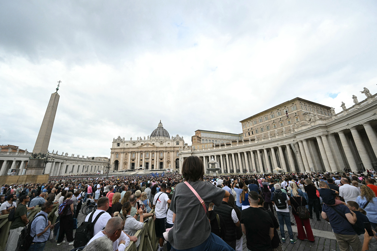 El Papa, vestido de blanco, levanta la mano en forma de saludo mientras sonríe desde una ventana del Palacio Apostólico
