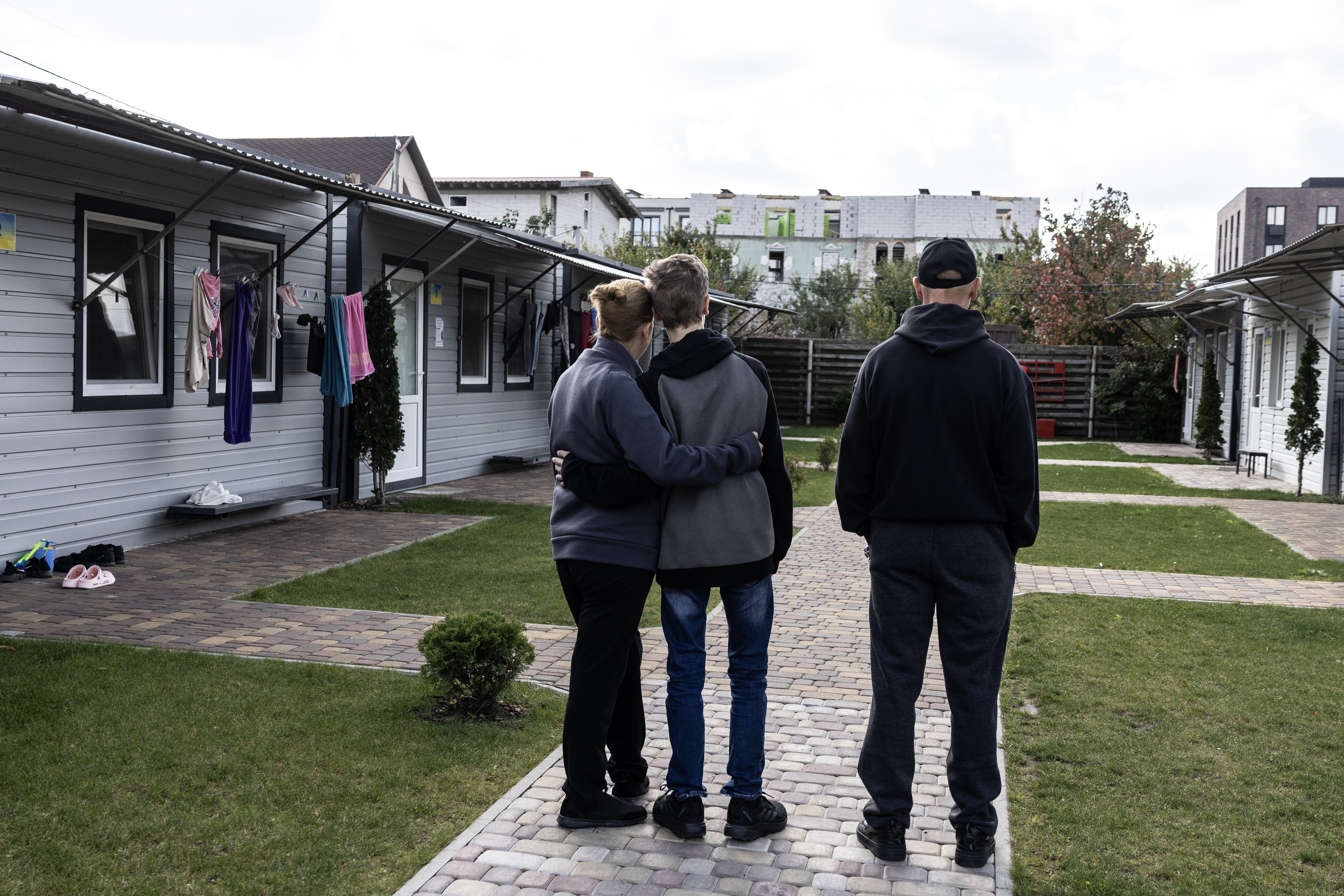 Vitaly, his wife, Iryna, and their 13-year-old son stand outside a complex in Kyiv for displaced Ukrainians. They survived the summer in Oleshky by sharing one cup of rice or buckwheat each day. (Heidi Levine/For The Washington Post)