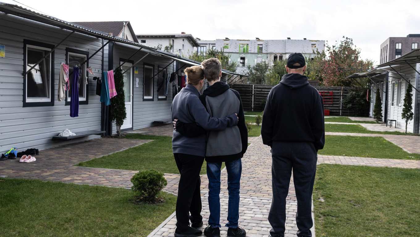 Vitaly, his wife, Iryna, and their 13-year-old son stand outside a complex in Kyiv for displaced Ukrainians. They survived the summer in Oleshky by sharing one cup of rice or buckwheat each day. (Heidi Levine/For The Washington Post)